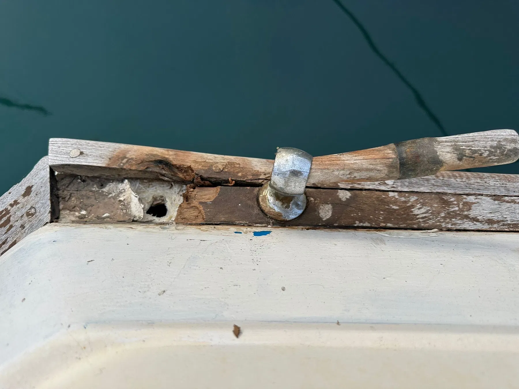 Geschädigtes Boot SANKARA – Detail am Heckdeck mit offenliegendem Holz, Beschlag und Öffnung im Befestigungsbereich.