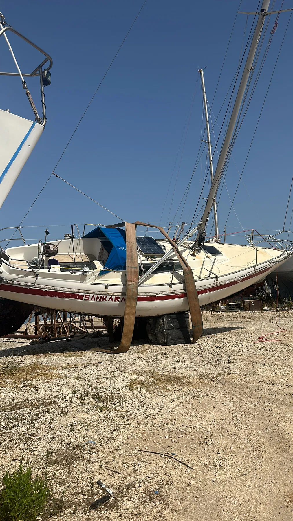 Geschädigtes Boot SANKARA – Gesamtansicht an Land mit sichtbarem Bootsnamen und abgestütztem Rumpf.