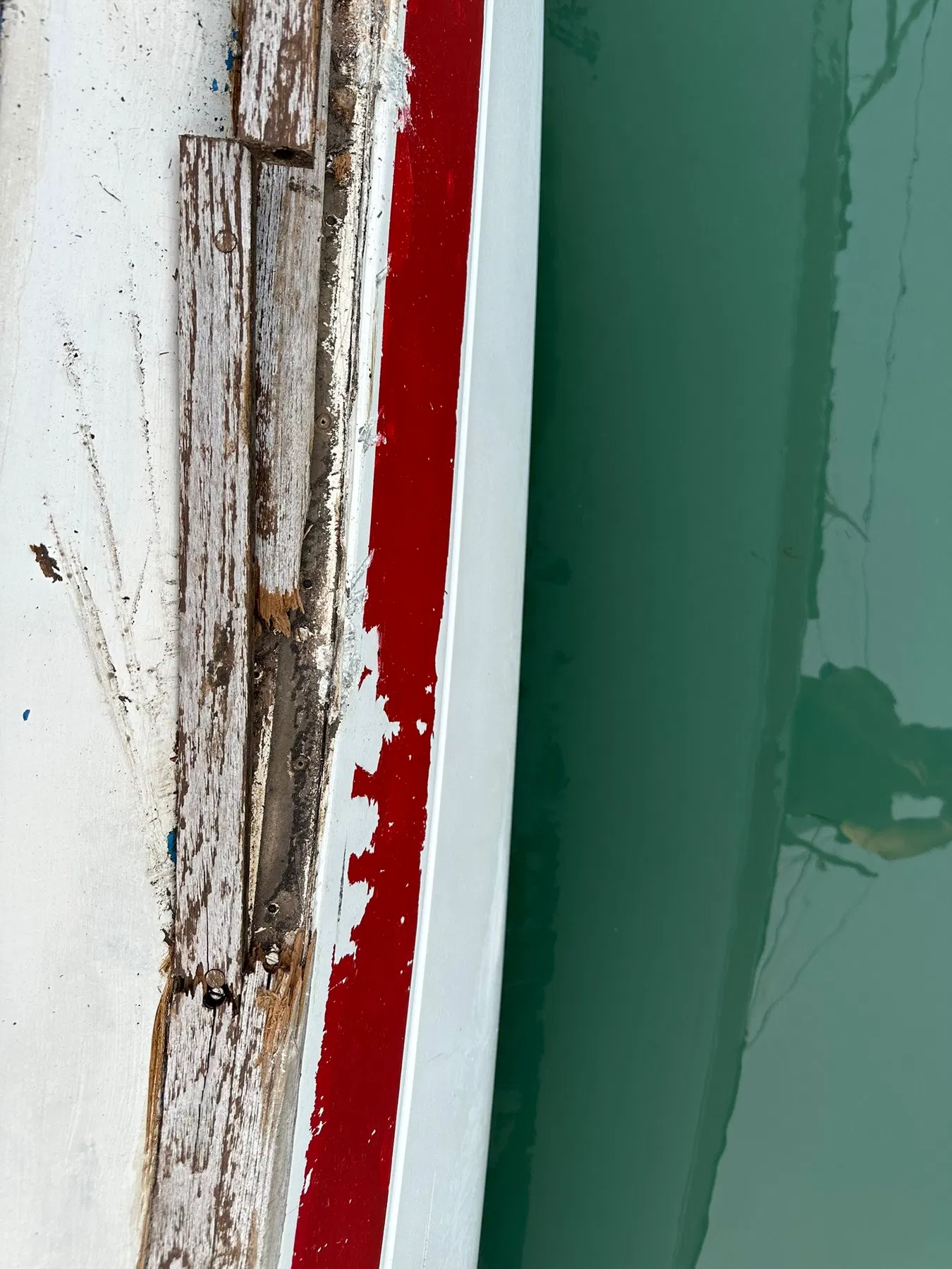Geschädigtes Boot SANKARA – Nahaufnahme einer beschädigten beziehungsweise geöffneten Holzkante am Übergang von Deck und Rumpf.