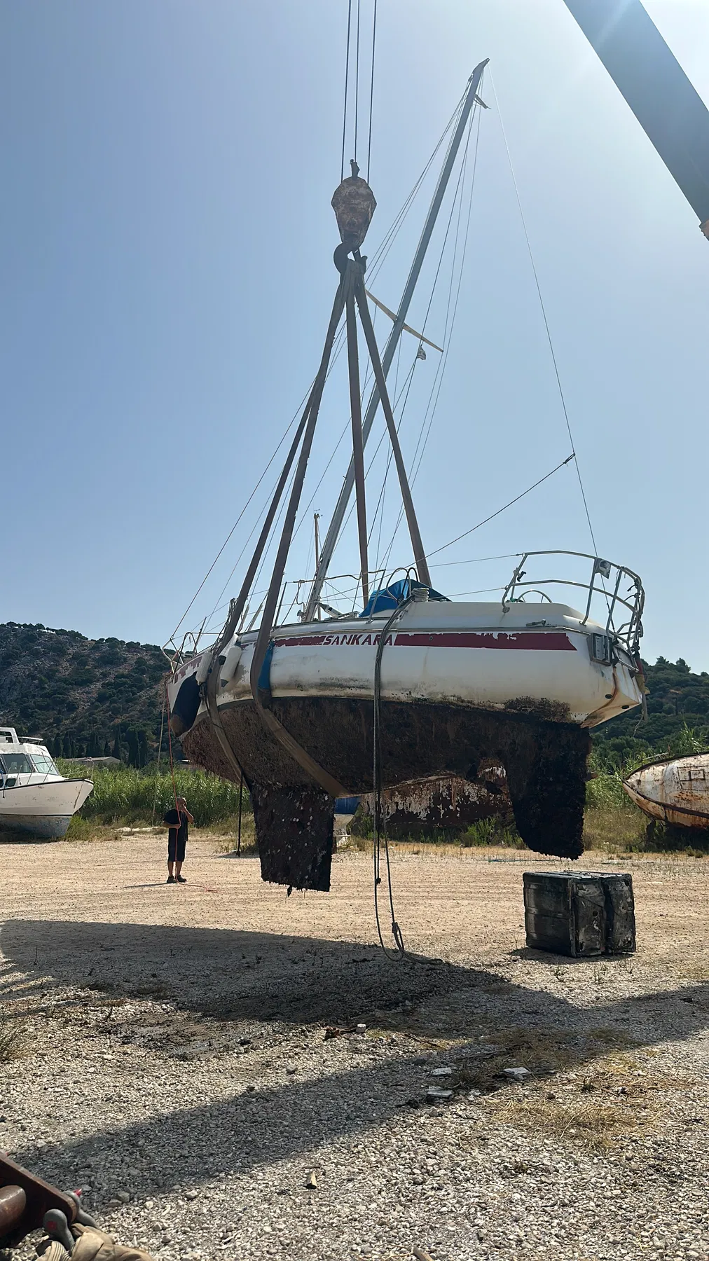 Geschädigtes Boot SANKARA – Ansicht an Land von achtern mit Rumpf, Kiel und Abstützung.