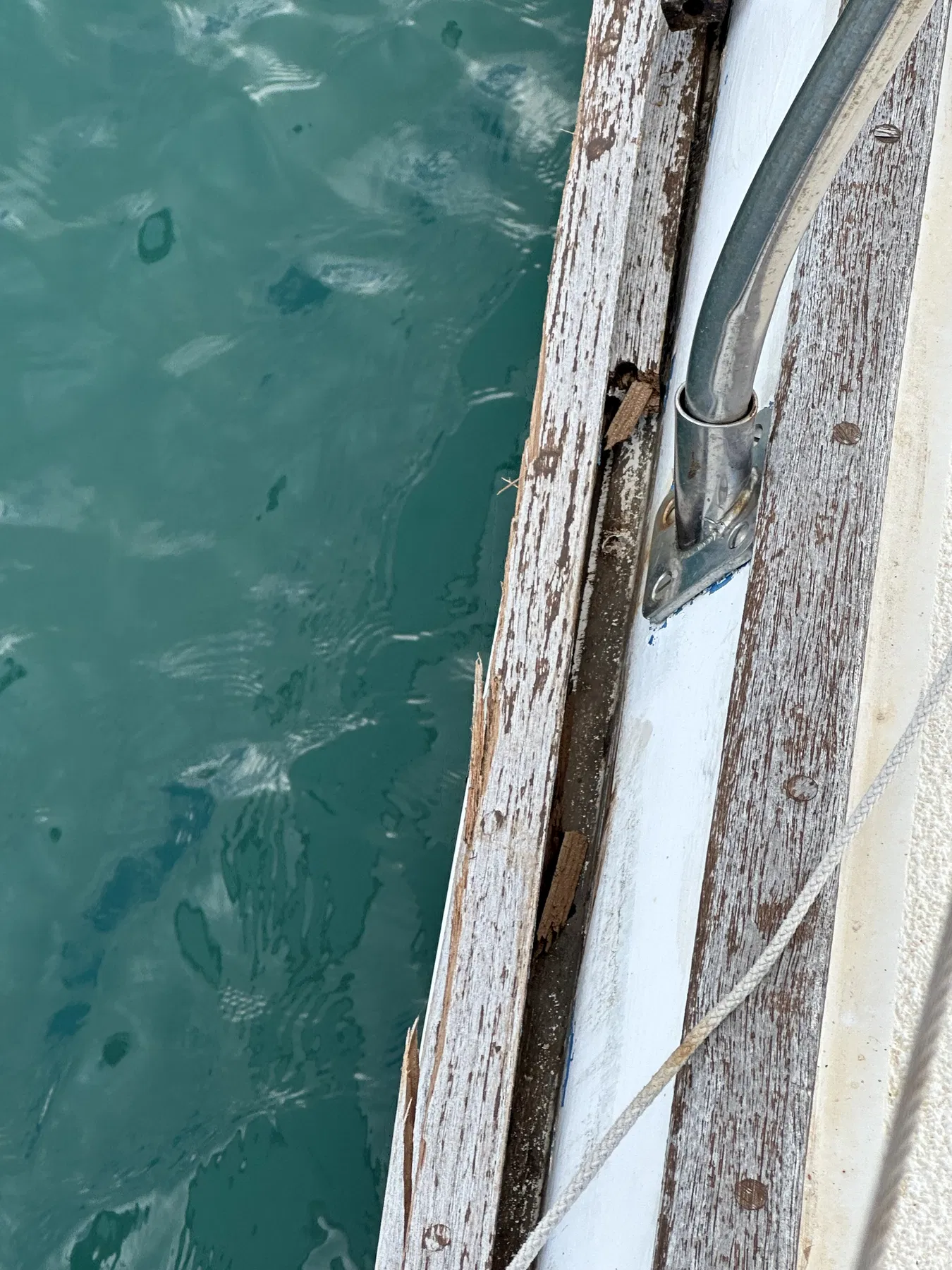 Geschädigtes Boot SANKARA – Nahaufnahme der hölzernen Deckskante und eines Metallbeschlags.