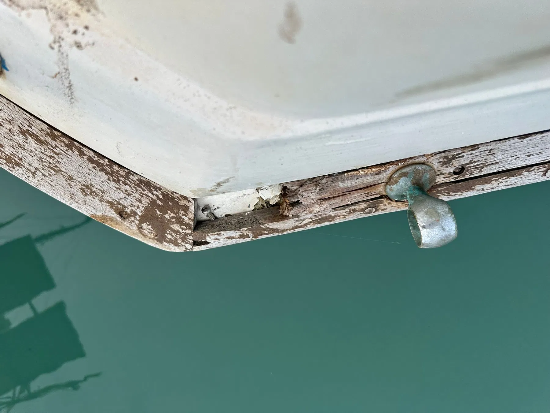 Geschädigtes Boot SANKARA – Heckkante mit Beschlag, Holzeinfassung und sichtbarer Öffnung im Befestigungsbereich.